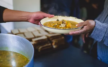 One hand handing another hand a bowl of food