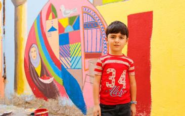Boy in front of a colorful mural