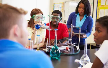 Teacher and high school students in chemistry lab