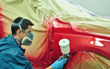 Factory worker painting a car