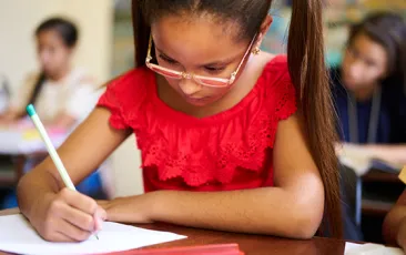 Young female student writing at school desk