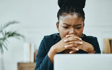 Shot of a young businesswoman frowning while using a laptop