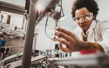 Black female engineer working on industrial machine in a laboratory