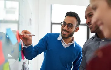 Portrait of an indian man in a diverse team of creative millennial coworkers in a startup brainstorming strategies