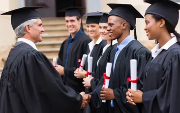 Professor handshaking with graduates
