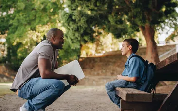 Mentor kneeling and talking to young boy
