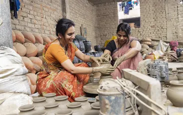 Two Indian women working at a pottery wheel