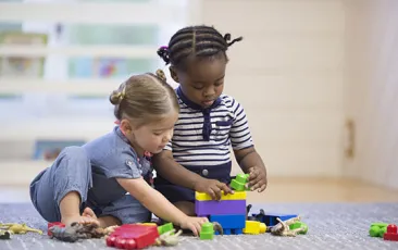 Toddlers playing on the floor with blocks