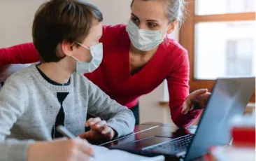 teacher and student wearing masks and talking while looking at a laptop