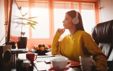 Teacher seated at computer wearing headphones
