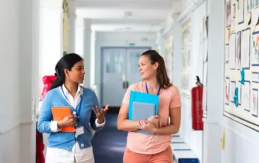 Two teachers walking down hallway and talking