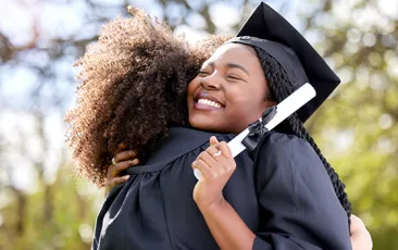 graduate hugging friend and holding diploma