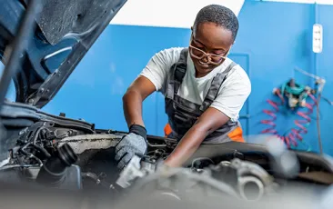 female mechanic working under hood of car