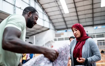 man helping woman in refugee shelter