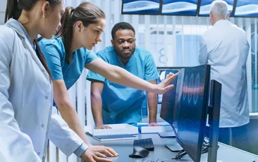 team of healthcare workers looking at computer monitor
