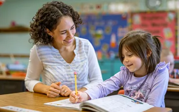 Teacher and young female student working together over a workbook