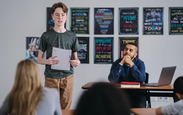 Middle school boy stands in class to do a presentation