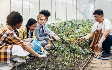 Teens learning about gardening from older adult