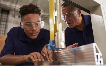 Carpenter training apprentice on mechanical saw