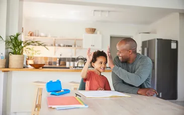 Dad and son high fiving over homework at kitchen island