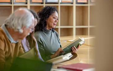 Woman reading in library with other adults