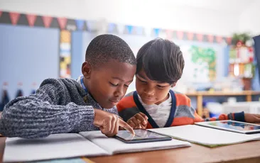 Two young students working together over an iPad
