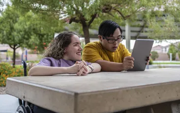 Friends with disabilities looking at an iPad together