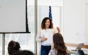 Teacher answering questions in front of a classroom