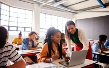 Teacher helping student at desk