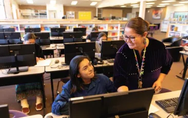 Teacher helping student in computer lab