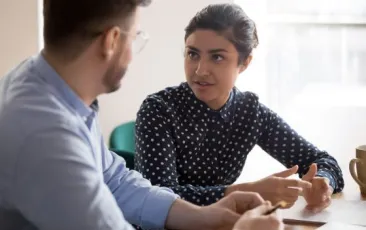Two teachers talking at table.