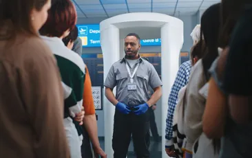 TSA worker in front of scanner
