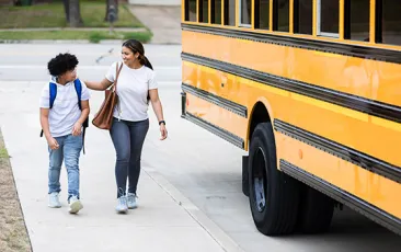 Mom walking preteen to schoolbus