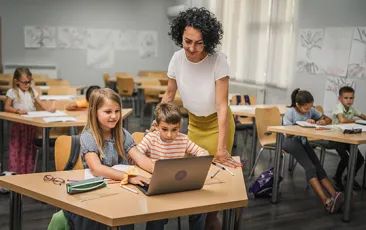 Elementary teacher with students over laptop