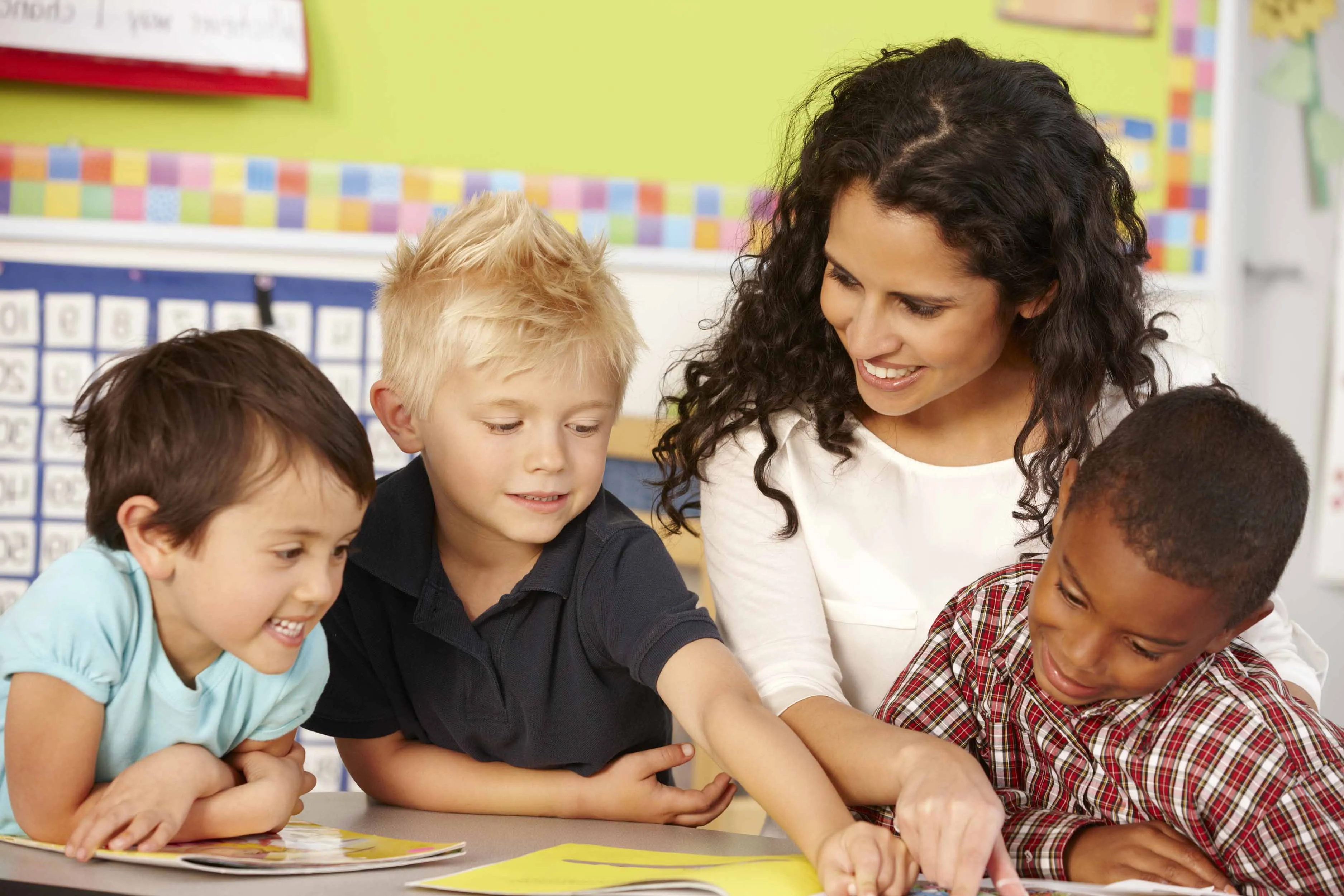 Teacher with happy young students working on a book
