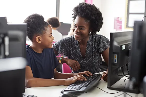 Teacher and student at desktop computer