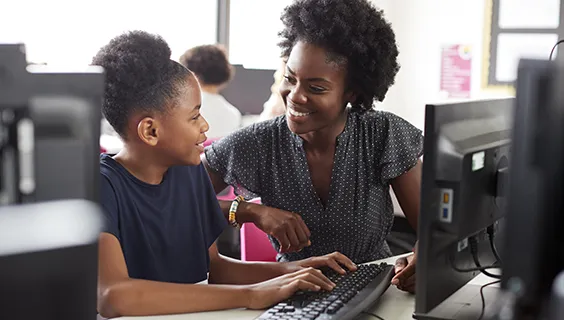 Teacher and student at desktop computer