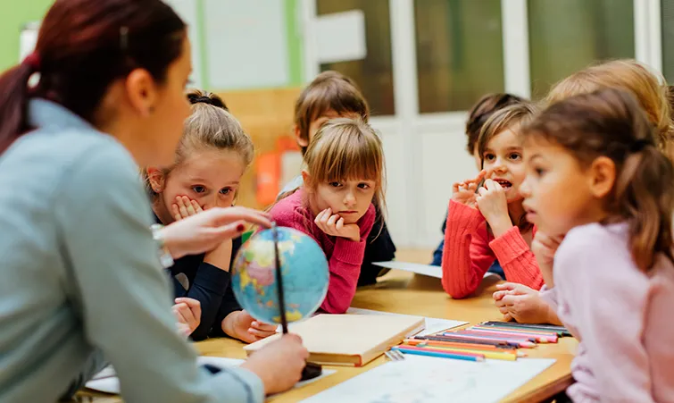 Social studies teacher with a globe and young students