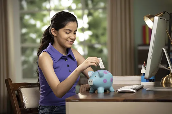 girl putting money in piggy bank