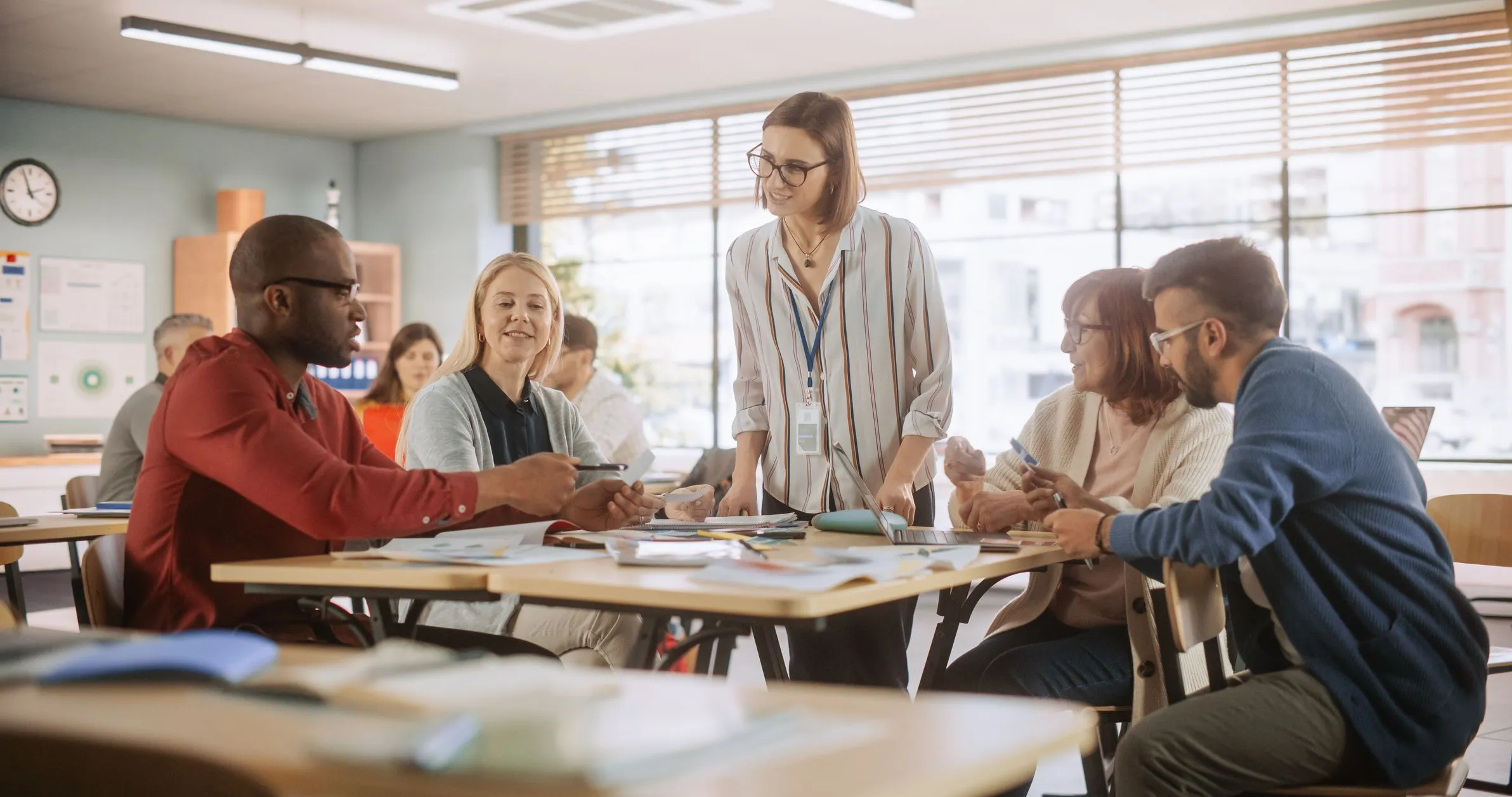 Teachers talking at desks in a classroom