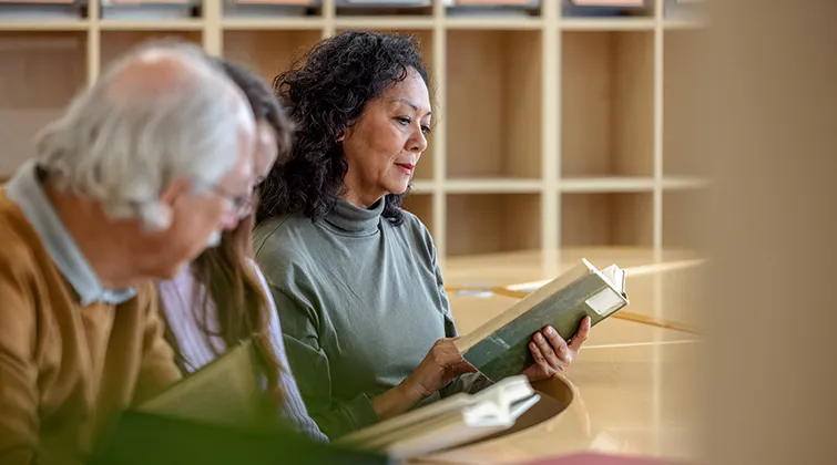 Woman reading in library with other adults