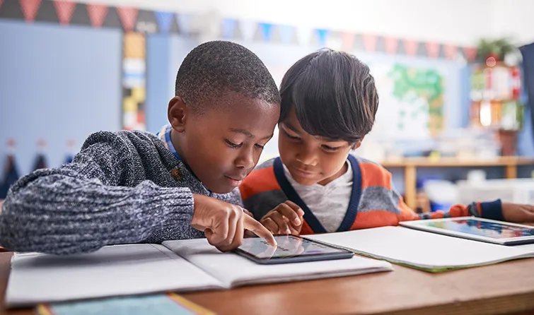 Two young students working together over an iPad