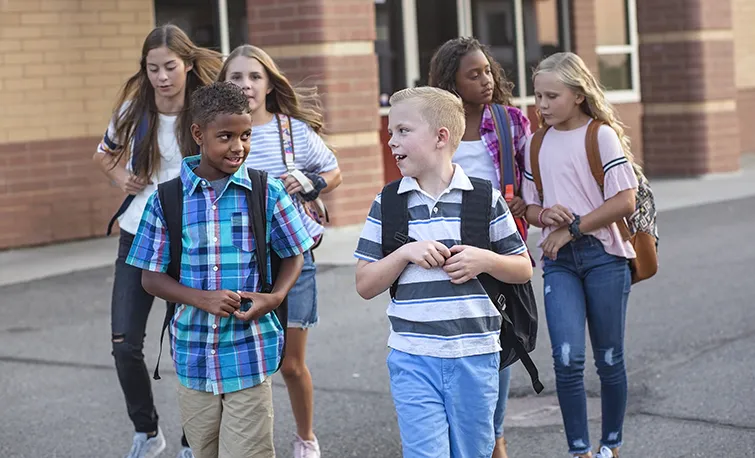 Happy kids leaving school building