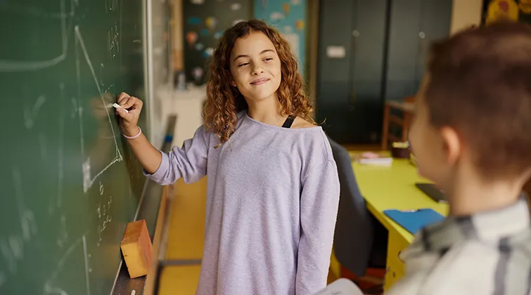 Young student doing a math problem at chalkboard