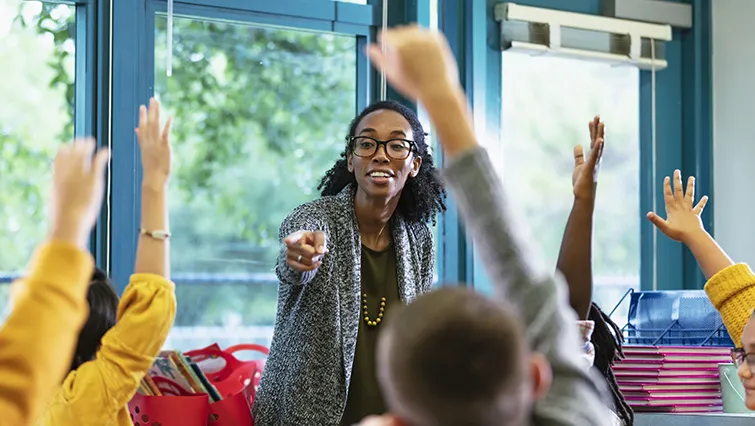 Young teacher with students raising their hands