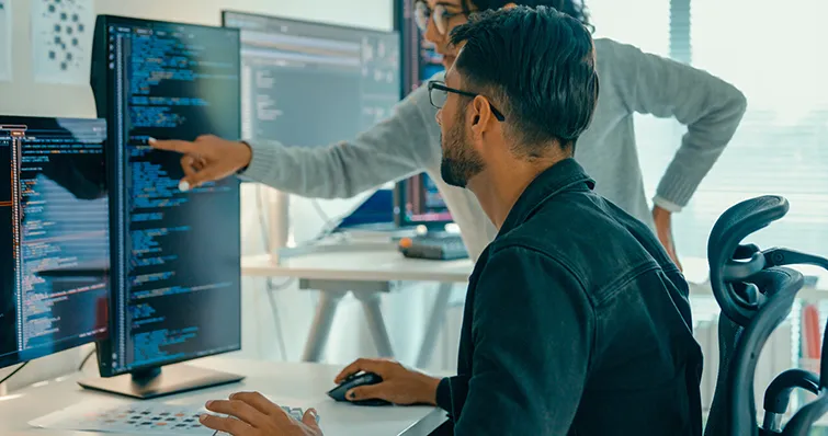 Man with colleague examining code on computer