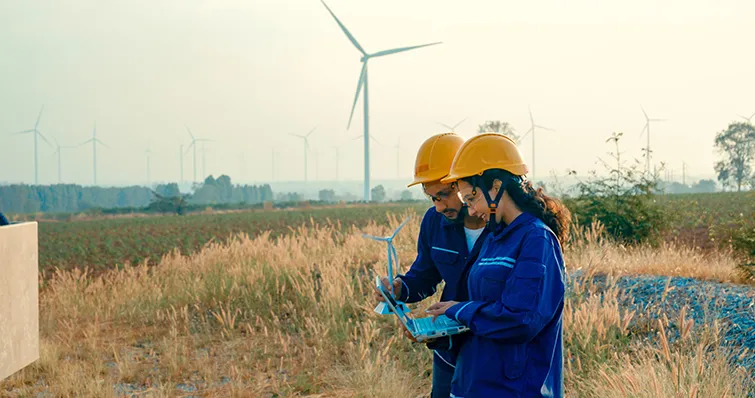 Workers in a field with wind turbines
