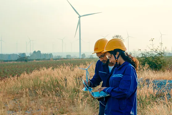 Workers in a field with wind turbines