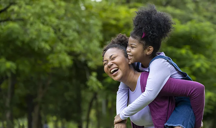 Mother and daughter laughing outside