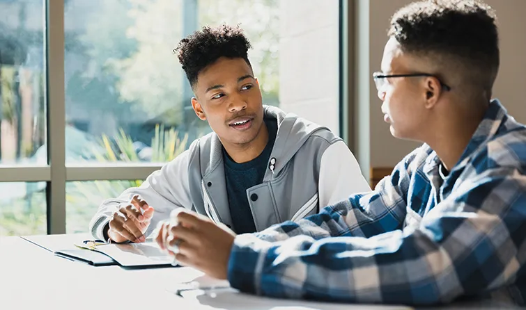 Two high school students talking in library